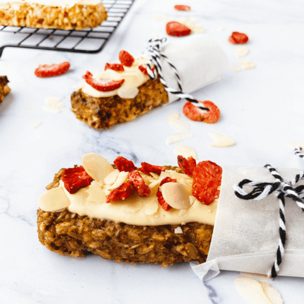 Zelfgemaakte gezonde granola bars met noten, amandelschaafsel en stukjes aardbei op een lichte ondergrond