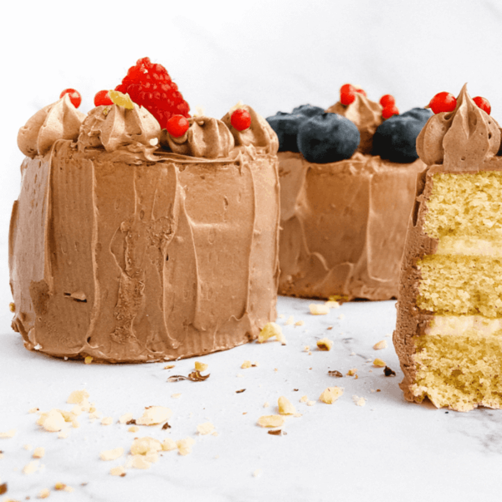 Koolhydraatarme room cupcakes met romige chocoladetopping en vers fruit op een lichte achtergrond