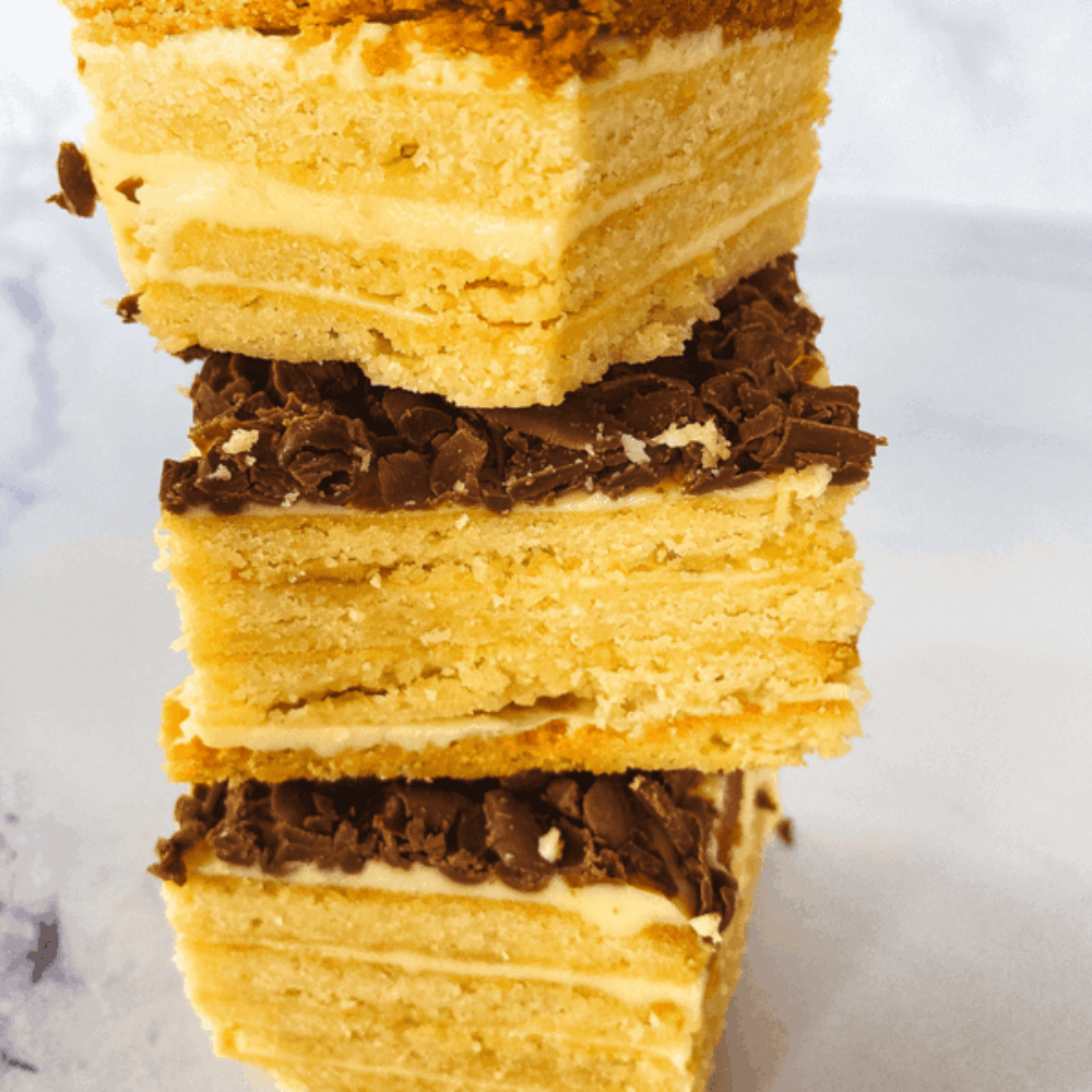 Koolhydraatarme petit beurre koekjes met romige roomboterlaag en chocoladeschilfers op een lichte achtergrond