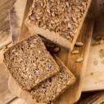 Gezond koolhydraatarm zadenbrood met zonnebloempitten en pompoenpitten op een houten snijplank