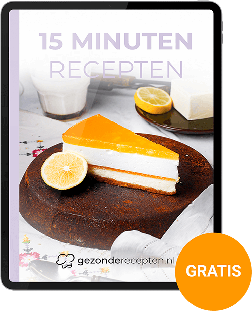 Tablet met de cover van het gratis digitale kookboek "15 Minuten Recepten" met een plakje no-bake cheesecake met citrusgelei op een donker, rustiek bord, gegarneerd met een schijfje citroen, van Gezonderecepten.nl.