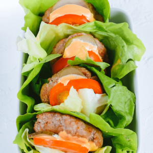 Meerdere sla wrap burgers met vlees, tomaat, augurk en romige oranje saus. Een gezonde, koolhydraatarme en keto vriendelijke variant van de klassieke burger van Gezonderecepten.nl.