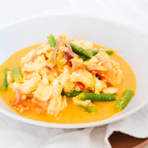 Een kom met romige oranje chili vispannetje met witte vis, sperziebonen en rode ui — een snelle, gezonde, koolhydraatarme en keto-vriendelijke maaltijd van Gezonderecepten.nl.