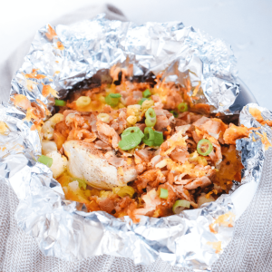 Een ronde met folie beklede ovenschaal met gebakken kip, gesmolten kaas, krokante ui en lente-ui — een heerlijke, eenvoudige, koolhydraatarme en keto-vriendelijke ovenschotel.