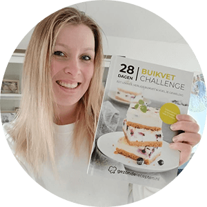 Een persoon houdt het hardcover kookboek "28 Dagen Buikvet Challenge," een koolhydraatarm dieetplan voor gewichtsverlies en het aanpakken van buikvet — een tevreden klant van Gezonderecepten.nl.