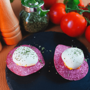 Twee hapjes van salami met een bolletje mozzarella erop, bestrooid met gedroogde kruiden en zwarte peper — een eenvoudige keto en koolhydraatarme appetizer voor gewichtsverlies en gezond dieet.