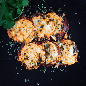 Kleine ronde, pizza achtige hapjes op een donker bord, met gesmolten goudbruine kaas. Een koolhydraatarme keto snack voor gewichtsverlies en gezond dieet.