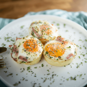 Drie keto eimuffins gemaakt van hele eieren gebakken in krokante hamcupjes, gegarneerd met peterselie en Parmezaanse kaas — een perfecte low-carb en gezonde ontbijtoptie