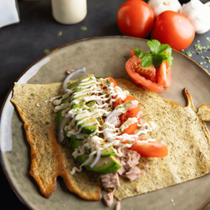 Hartige cottage cheese flatbread sandwich gevuld met tonijn, avocado en rode ui, overgoten met romige saus en geserveerd met tomaat en knoflook, perfect voor keto, low-carb dieet en gezond afvallen.