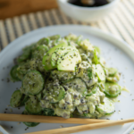 Romige keto komkommersalade met stukjes avocado, sesamzaad en een lichte dressing, geserveerd met stokjes en sojasaus — een verfrissend low-carb gerecht ideaal voor een gezond keto dieet en gewichtsverlies.