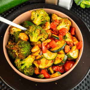Een kom met airfryer-garnalen en geroosterde groenten zoals broccoli, courgette, rode paprika en cherrytomaten, een kleurrijk koolhydraatarm gerecht voor gewichtsverlies en een gezond dieet
