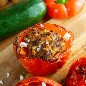 Gehalveerde rode paprika’s uit de airfryer gevuld met een hartige kipvulling en afgetopt met verkruimelde fetakaas, geserveerd met courgette en andere paprika’s — een mediterraanse koolhydraatarme maaltijd voor gezond gewichtsverlies en dieet.