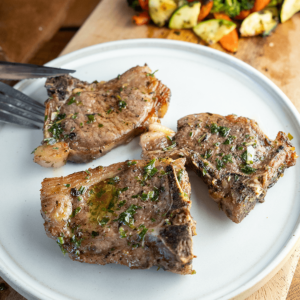 Koolhydraatarme lamskoteletjes met geroosterde groenten gegarneerd met peterselie. Een smakelijke koolhydraatarme maaltijd voor gewichtsverlies en gezond eten.