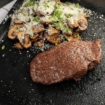 Een sappige airfryer biefstuk geserveerd met gebakken champignons, Parmezaan en kruiden — een smaakvolle koolhydraatarme maaltijd voor gezond afvallen en diëten.