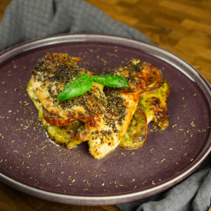 Een gebakken kipfilet met tomaat, gesmolten kaas, gedroogde kruiden en een verse basilicumblad — een koolhydraatarme maaltijd voor gewichtsverlies en een gezond dieet