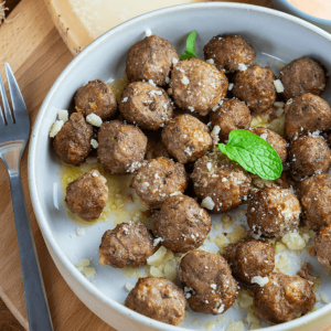 Plate of healthy keto air-fried meatballs with parmesan and fresh garnish, served with a fork