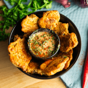 Een kom met goudbruine Keto kipnuggets met dip gegarneerd met gehakte kruiden. Een heerlijke koolhydraatarme snack, perfect voor het keto dieet en gewichtsverlies.