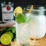 Keto mojito met rum geserveerd in een hoog, gestructureerd glas met ijs, verse muntblaadjes en een limoenpartje. Een verfrissend koolhydraatarm drankje voor gewichtsverlies en een gezond dieet.