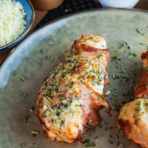 Kipfilets gevuld met mozzarella en omwikkeld met knapperig spek, gegarneerd met gesmolten kaas en verse kruiden — een heerlijke koolhydraatarme maaltijd voor gewichtsverlies en een gezond dieet