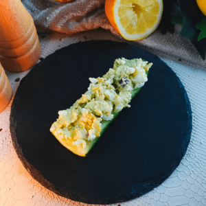 Een keto komkommerbootje gevuld met romige eiersalade, geserveerd op een zwart leisteenbord met een halve citroen op de achtergrond ideaal voor een koolhydraatarm keto dieet en gezond gewichtsverlies.