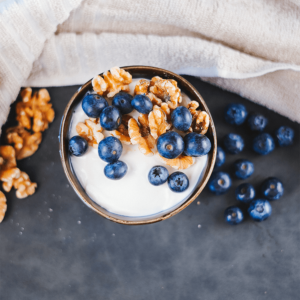 Een kom romige Griekse yoghurt met verse blauwe bessen en knapperige walnoten, met losse bessen eromheen — een gezond ontbijt dat de darmgezondheid ondersteunt en helpt bij gewichtsverlies.