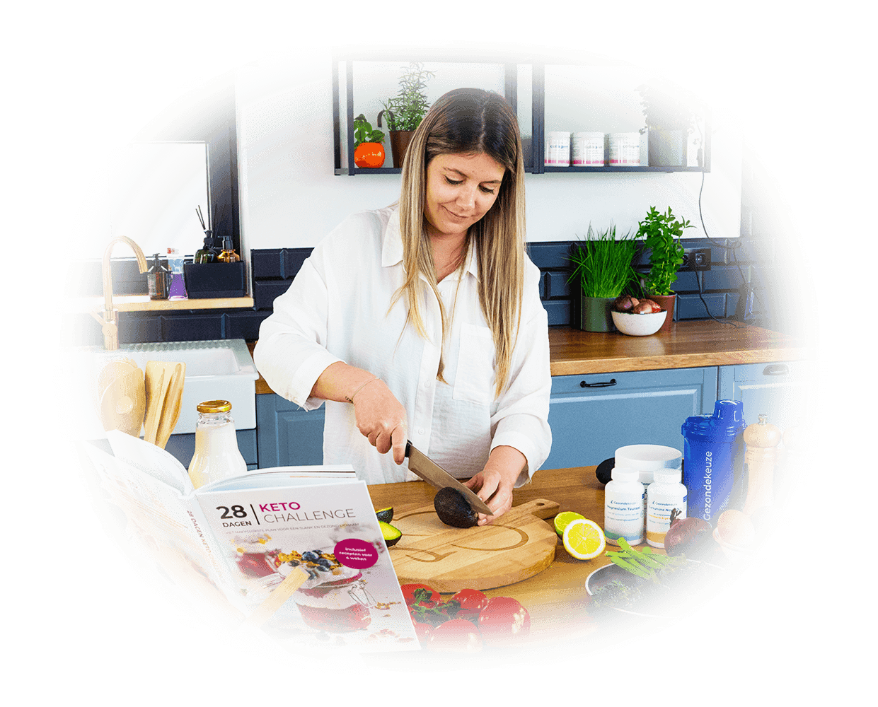 Een vrouw in de keuken snijdt een avocado naast het boek 28 DAGEN KETO CHALLENGE, omringd door verse ingrediënten en keukenspullen, toont koolhydraatarme en keto recepten uit de 28 Dagen Keto Challenge