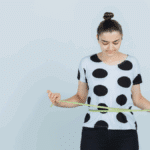 Een vrouw gebruikt een meetlint rond haar taille om haar voortgang in gewichtsverlies te controleren