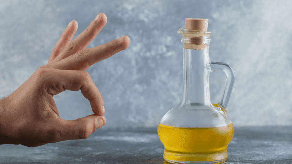 Hand die goedkeurend gebaar maakt naast een fles olijfolie op tafel