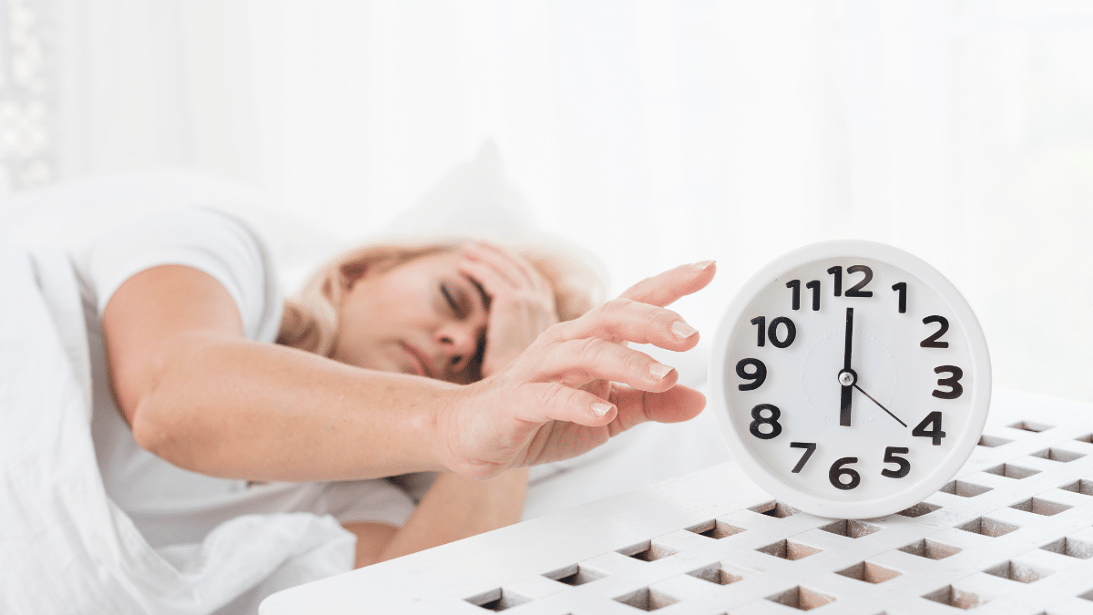 Vrouw die wakker wordt en haar wekker uitzet in de ochtend