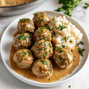 Paleo Zweedse gehaktballetjes met romige jus op een bord, geserveerd met zachte bloemkoolpuree en verse peterselie. Perfect gerecht voor een gezonde, graanvrije en zuivelvrije maaltijd in IKEA stijl.