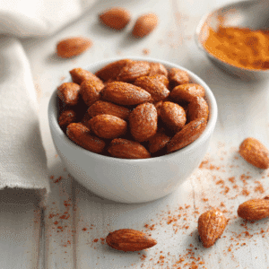 Geroosterde amandelen gekruid met paprika, geserveerd als een gezonde snack. De amandelen zijn goudbruin en bedekt met een kruidenmengsel van gerookte paprika, die een subtiele rokerige en pittige smaak aan de noten toevoegt.