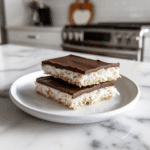 Paleo niet gebakken kokosrepen met pure chocoladelaag, gemaakt van kokosrasp, kokosolie en donkere chocolade.