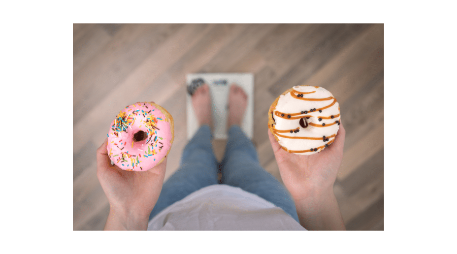Illustratie van een persoon die op een weegschaal staat en twee donuts vasthoudt, als symbool voor hoe suiker en bewerkte producten invloed hebben op gewicht en gezondheid.