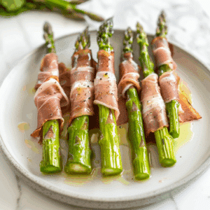 Prosciutto omwikkelde asperges met dunne, zoute ham rond heldergroene asperges, licht besprenkeld met olijfolie en zwarte peper voor een krokante, Paleo vriendelijke hartige snack of bijgerecht.