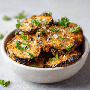 Keto aubergine met krokante amandelkorst, besprenkeld met olijfolie en gegarneerd met verse peterselie – koolhydraatarm en gezond bijgerecht
